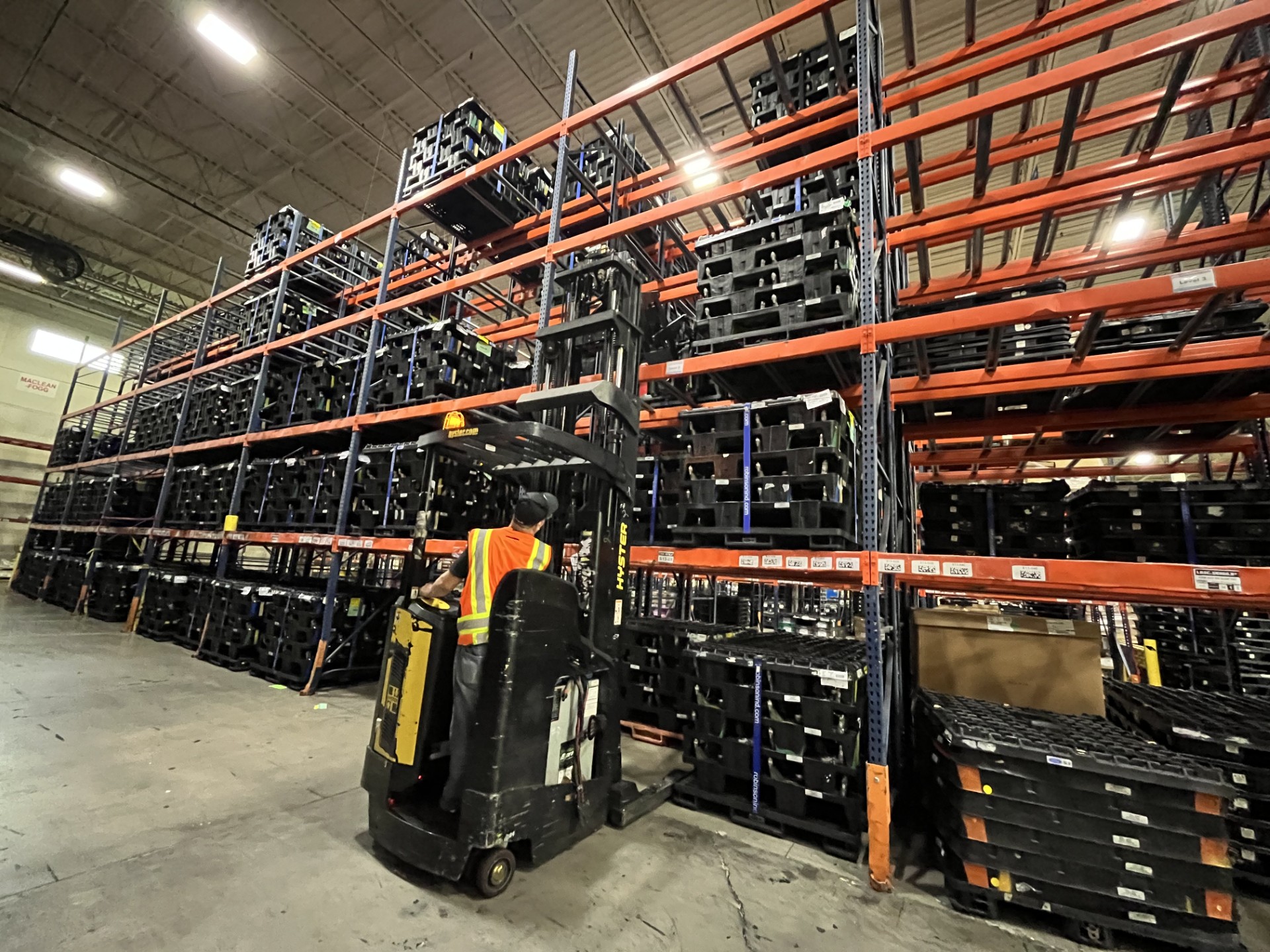 Worker operating forklift in double deep racking system