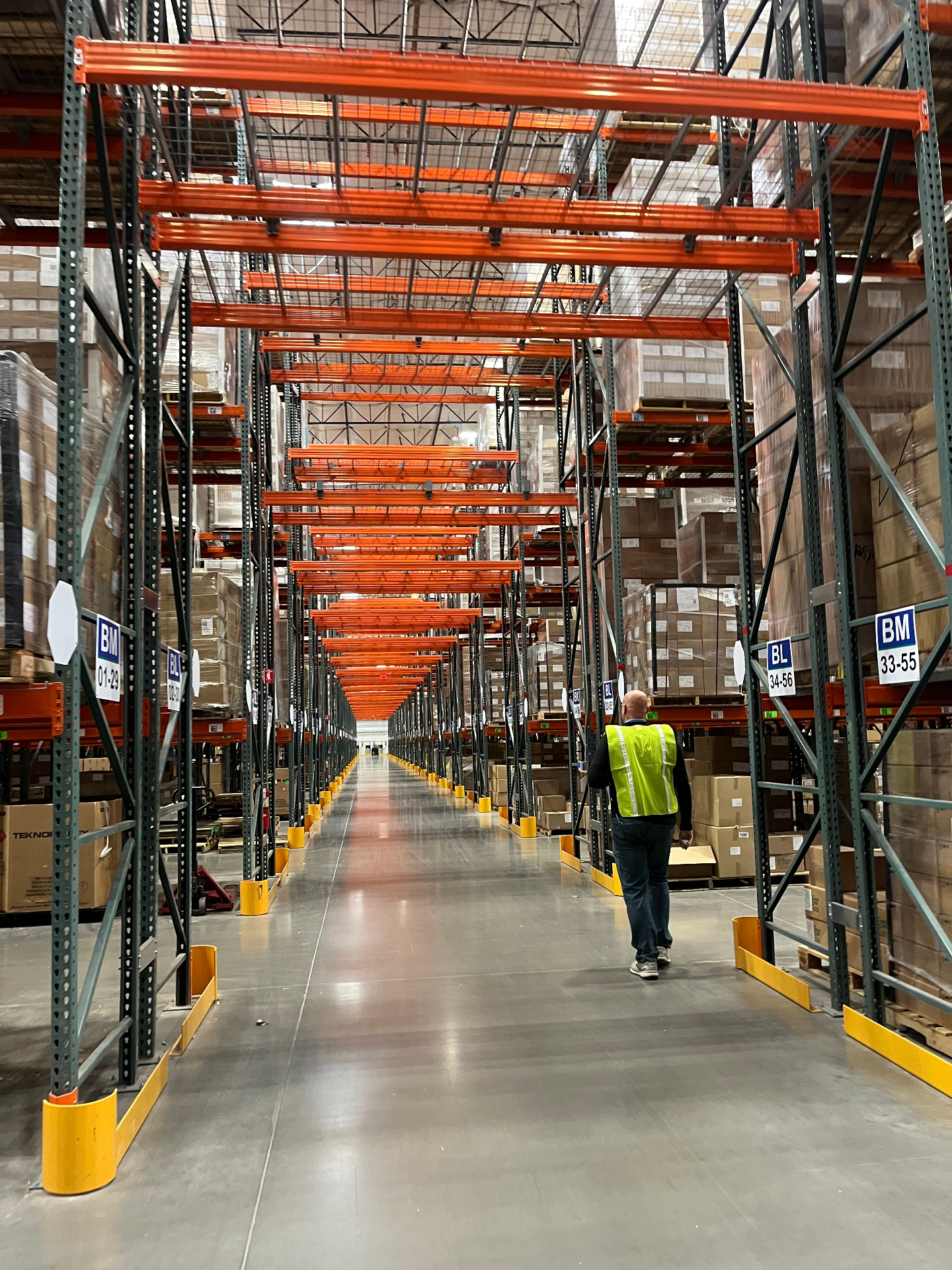 Warehouse aisle with orange selective racking and worker